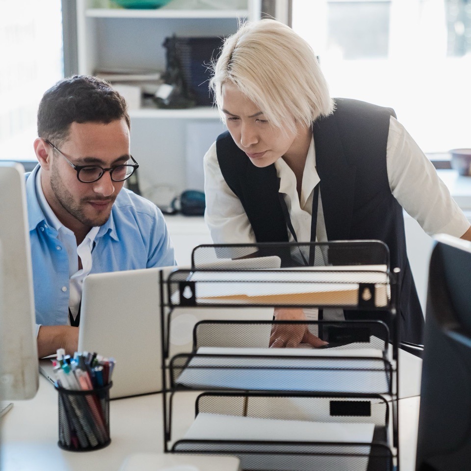 Twee professionals die tijdens onboarding samenwerken achter een laptop